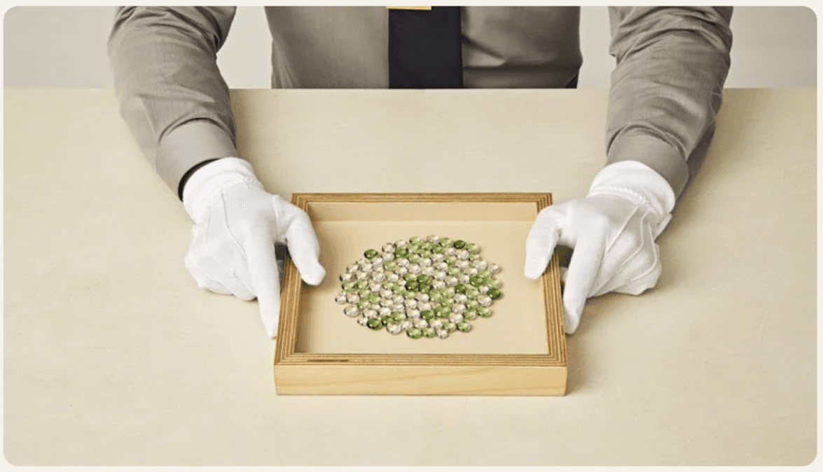 A gloved attendant presenting a tray of finished Selah Stones